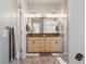 Modern main bathroom with dual vanities, a large mirror, and a glass-enclosed shower at 1857 W 67Th Pl, Denver, CO 80221