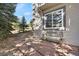 View of stone patio with seating, mature trees, and siding detail at 481 Sunrise Dr, Golden, CO 80401