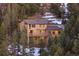 View of house exterior surrounded by pine trees and snow covered ground at 29011 Upper Moss Rock Rd, Golden, CO 80401