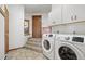 Convenient laundry room with modern washer and dryer, tile floor, and wooden cabinets at 29011 Upper Moss Rock Rd, Golden, CO 80401