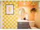 Stylish bathroom featuring a gray vanity, round mirror, pendant plant and yellow checkered walls at 4520 S Delaware St, Englewood, CO 80110