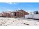 Cute brick ranch home with a white picket fence and snow covered yard at 501 S Dale Ct, Denver, CO 80219