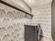 Laundry room with patterned wallpaper, floating shelves, and a side-by-side washer and dryer at 10570 Worchester Dr, Commerce City, CO 80022
