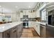 Bright kitchen features an island, stainless appliances, white cabinetry and wood-look floors at 3165 W 63Rd Ave, Denver, CO 80221