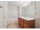 Bathroom featuring a vanity with wood cabinetry, a large mirror with decorative lighting, and a shower-tub combo at 4875 S Balsam Way # 6-102, Littleton, CO 80123