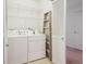 Bright laundry room with white washer and dryer, overhead storage, and a convenient step ladder for easy access at 4875 S Balsam Way # 6-102, Littleton, CO 80123