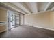 Bright living room with exposed beam ceilings, carpet floors, and sliding glass doors to a patio area at 4801 E 9Th Ave # 108S, Denver, CO 80220
