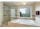 Bright bathroom featuring a soaking tub, walk-in shower, large window, and neutral tile at 31 N Algonquian St, Aurora, CO 80018
