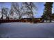 Rear view of a mid-century modern home with wood siding and snowy yard at 6127 S Westview St, Littleton, CO 80120