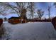 Rear view of a mid-century modern home with wood siding and snowy yard at 6127 S Westview St, Littleton, CO 80120