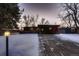 Mid-century modern home with wood siding, snowy yard, and driveway at 6127 S Westview St, Littleton, CO 80120