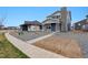 New construction two-story home featuring blue siding, brick chimney, gravel yard, and concrete sidewalk at 2267 Peregrine Dr, Brighton, CO 80601