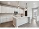 Bright kitchen featuring white cabinets, stainless appliances, a spacious island, and wood grain flooring at 2267 Peregrine Dr, Brighton, CO 80601