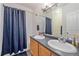 Bathroom showcasing a dual sink vanity, large mirror, and shower with a blue curtain at 14700 E 104Th Ave # 1602, Commerce City, CO 80022