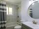 Well-lit bathroom featuring a shower-tub combination and modern vanity with a stylish round mirror at 11937 Claude Ct, Northglenn, CO 80233