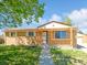 Charming brick home featuring a cozy porch and green lawn on a sunny day with blue skies at 11937 Claude Ct, Northglenn, CO 80233