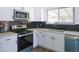Modern kitchen featuring white cabinets, stainless steel appliances, and a sleek black backsplash at 11937 Claude Ct, Northglenn, CO 80233