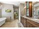 Well-appointed bathroom with double vanity, granite countertop, bathtub, and archway leading to living area at 11433 Decatur Ct, Westminster, CO 80234