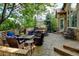 Stone patio featuring an outdoor kitchen, fire pit, and comfortable wicker seating surrounded by mature trees and lush landscaping at 11433 Decatur Ct, Westminster, CO 80234