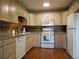 Well-lit kitchen featuring tan cabinetry, modern white appliances, and stylish backsplash at 9625 E Center Ave # 4C, Denver, CO 80247