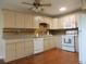 Well-lit kitchen featuring tan cabinetry, modern white appliances, and stylish backsplash at 9625 E Center Ave # 4C, Denver, CO 80247