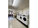 Functional laundry room with multiple washing machines, bulletin board, and seating at 9625 E Center Ave # 4C, Denver, CO 80247