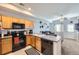 Open kitchen featuring wood cabinets, black appliances, and a breakfast bar overlooking the living area at 2235 Coronado Pkwy # A, Denver, CO 80229