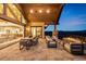 Spacious covered patio with dining and seating areas, and mountain views at twilight at 3148 Keep Dr, Sedalia, CO 80135