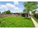 Lush backyard featuring a green lawn, brick accents, covered patio seating, and well-maintained wooden fencing at 2461 Niagara St, Denver, CO 80207