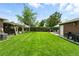 Well-kept backyard with green lawn, brick detailing, covered patio, wooden fence, and space for outdoor living at 2461 Niagara St, Denver, CO 80207