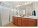 Bathroom featuring double vanity, large mirrors, and a glass shower enclosure at 8926 Swan River St, Littleton, CO 80125