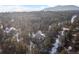 A high aerial view of the house nestled in a dense forest with mountains in the background at 2492 Baldy Ln, Evergreen, CO 80439