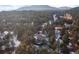 A high aerial view of the house nestled in a dense forest with mountains in the background at 2492 Baldy Ln, Evergreen, CO 80439