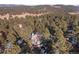 An aerial view of the house nestled in a dense forest in a mountain community at 2492 Baldy Ln, Evergreen, CO 80439