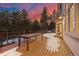 Spacious deck with railings, a table, and beautiful sunset views of the surrounding trees at 2492 Baldy Ln, Evergreen, CO 80439