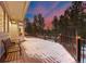 Spacious deck with railings, a bench, and beautiful sunset views of the surrounding trees at 2492 Baldy Ln, Evergreen, CO 80439