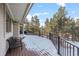 Expansive wood deck with metal railing, offering peaceful views of the surrounding trees and snow at 2492 Baldy Ln, Evergreen, CO 80439