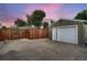 Large detached two car garage with white doors, a privacy fence, and a cracked concrete driveway at 4329 S Clarkson St, Englewood, CO 80113