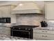 Gourmet kitchen with black stove, grey brick backsplash, custom cabinets, and granite countertops at 3124 Antelope Ridge Trl, Parker, CO 80138