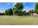 Expansive backyard with mature trees, a wooden fence, and outbuildings on a well-maintained lawn at 1813 Pikes Peak St, Erie, CO 80516