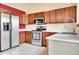 Modern kitchen boasts stainless steel appliances, wood cabinetry, and white tile floors at 13008 Grove Way, Broomfield, CO 80020