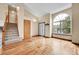 Open-concept room featuring hardwood floors, a large arched window, staircase, and white door at 13008 Grove Way, Broomfield, CO 80020
