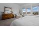Serene bedroom with a cozy chair and dresser, bathed in natural light from the large windows, promoting relaxation at 6456 Kenzie Cir, Castle Pines, CO 80108