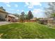 Lush backyard features a large lawn, mature trees, garden beds, and perimeter fencing at 2588 S Flower Ct, Lakewood, CO 80227