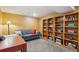 Basement area with yellow walls, gray sofa, shelving and a desk at 2588 S Flower Ct, Lakewood, CO 80227