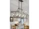 Modern chandelier over kitchen island with open dining area and light colored cabinets in the background at 2588 S Flower Ct, Lakewood, CO 80227