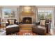 Cozy living room with a brick fireplace, wood mantel, and comfortable chairs and ottomans next to large windows at 2588 S Flower Ct, Lakewood, CO 80227