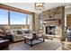 Comfortable living room with stone fireplace, large windows with mountain views, and hardwood floors at 1052 Country Club Estates Dr, Castle Rock, CO 80108