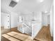 Hallway with light hardwood floors, white railings, and natural light streaming in through windows at 13058 Monaco Way, Thornton, CO 80602