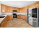 Well-lit kitchen featuring stainless steel appliances, wood cabinets, and modern flooring at 13058 Monaco Way, Thornton, CO 80602